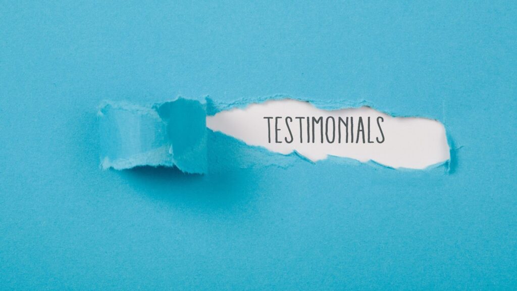 Light blue background paper material with the word "Testimonials" ripped out in the center. Topic: testimonials in marketing