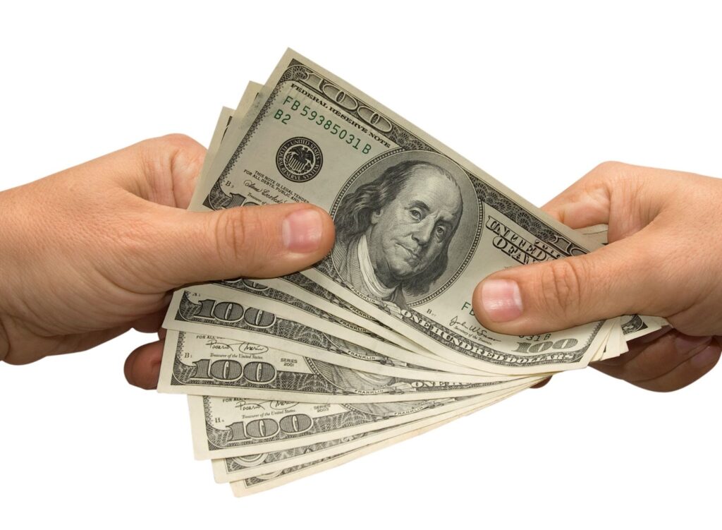 Two hands exchanging handful of $100 bills. Topi: hiring digital freelancers