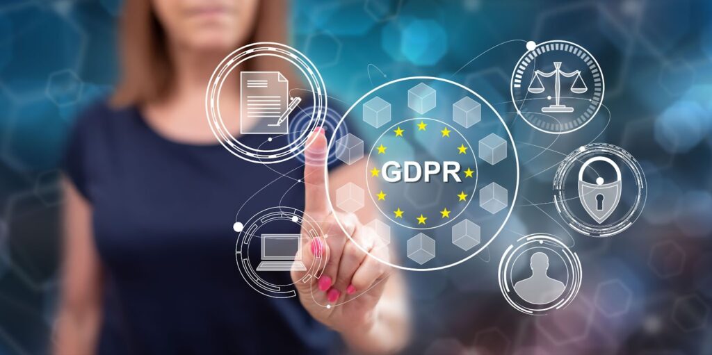 Blurred image of woman in the background. Foreground shows woman's index finger pointing at different images which all surround a larger circle that reads "GDPR" surrounded by border of yellow starts in circle. Other smaller graphics include a document with pen, computer screen, law symbol, lock symbol, and silhouette of a head. Topic:  GDPR for us-based websites